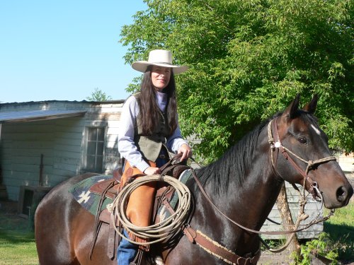 A nice looking lady with cowgirl hat on a horse.