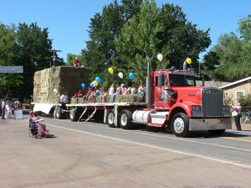 A flatbed truck with a load of hay and lots of riders