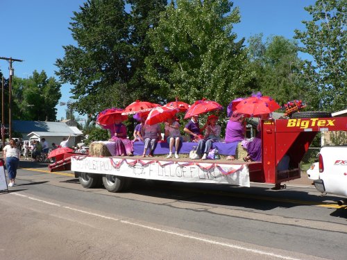 A flatbed with women dressed in scarlet and umbrellas.