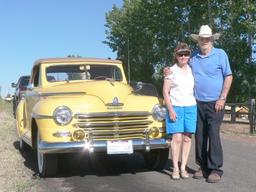 A Yellow 1940's car with man and wife posing.