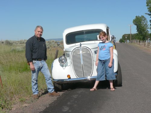 Man and daughter pose in front of 1940's white pickup.