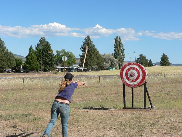 Young lady throws axe at a round target.