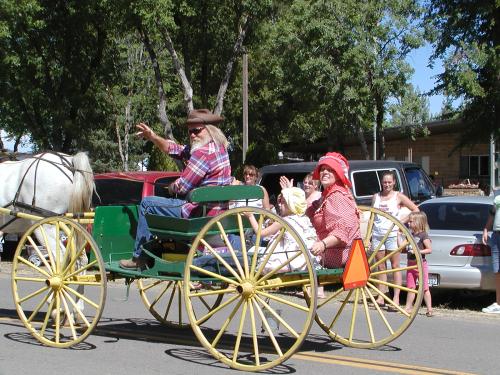 An arabian horse pulling a wagon with Husband, wife and daughter dressed in old western garb.