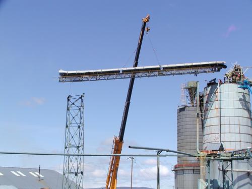 A long section of the damaged conveyor belt and nechahnism is being lowered to the ground by crane.