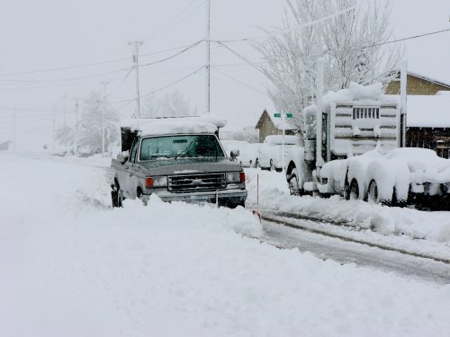 A pickup truck with snow plow plowing the road.
