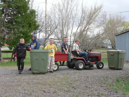 Boys with a garden tractor posing with 2 of the 3 garbage bins they filled. 