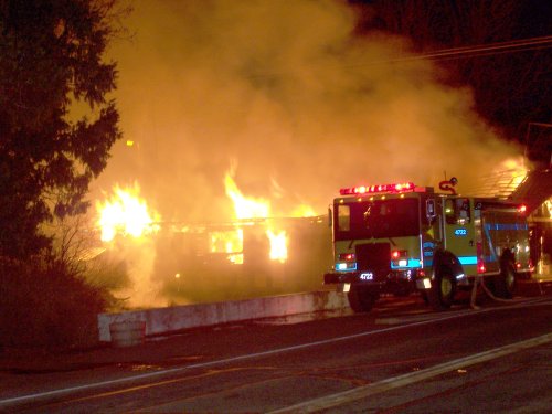 A burning building in the night with fire truck in foreground.