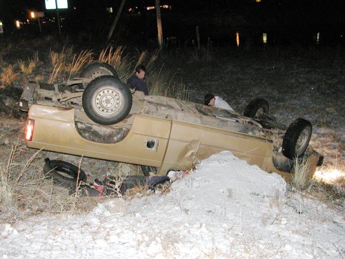 A brown pickup truck on it's back down an embankment.