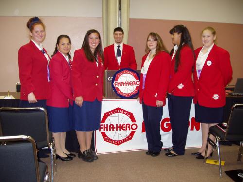 Students posing behind podium labeled California FHA Heo Association, dressed in red school uniforms.