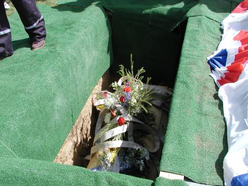 Looking into the grave with a fire hose laid on top of the casket.