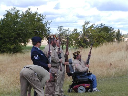 Adin VFW in uniform, one in a wheelchair with rifles.