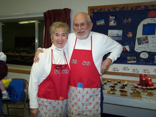 2 of the cooks in red aprons posing in the kitchen.