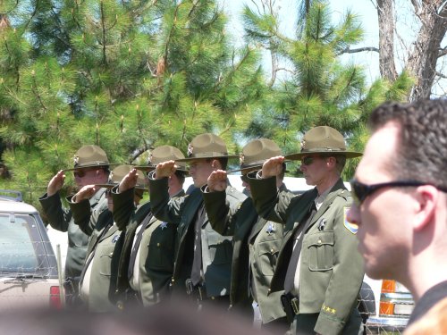 Fish and game persons in uniform give a formal salute.