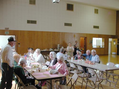 A group of seniors sitting at tables for a communal lunch.
