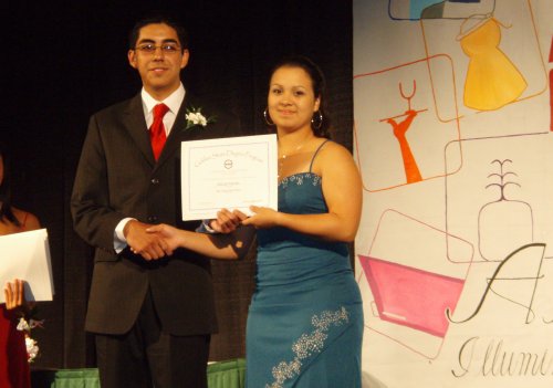 A young man and lady hold up their award.