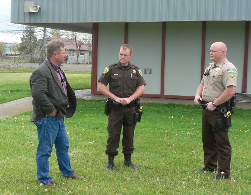 2 Sheriff's deputies in uniform satnd in front of school building and discuss plans with school super