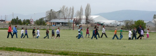 A long line of students cross the field to the evacuation center.