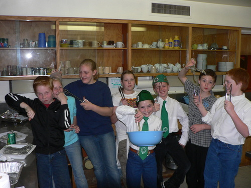 8 youngsters who helped at the crab feed pose in the kitchen having fun.