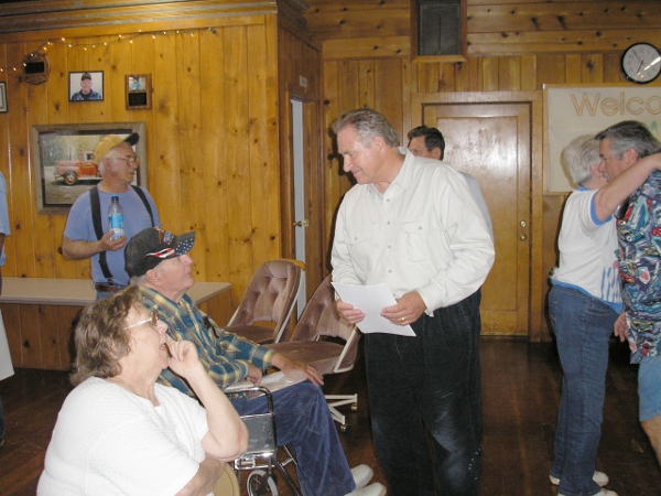 Man (Jim Nielson) speaks with seated citizens.
